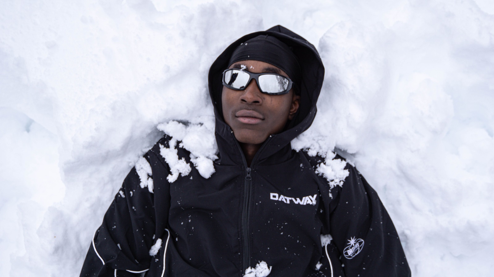 Un ragazzo sdraiato nella neve con gli occhiali a specchio