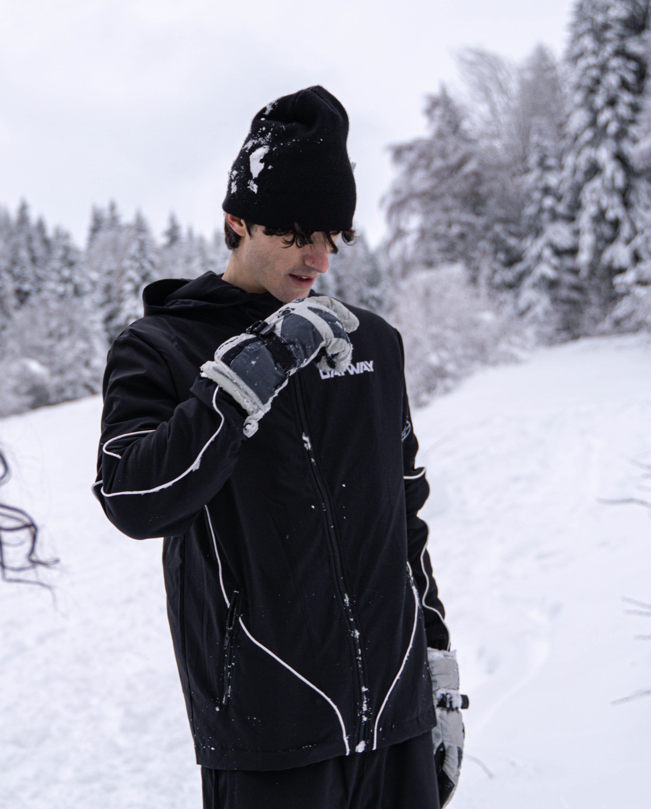 Un ragazzo con il berretto guarda in basso, nella neve