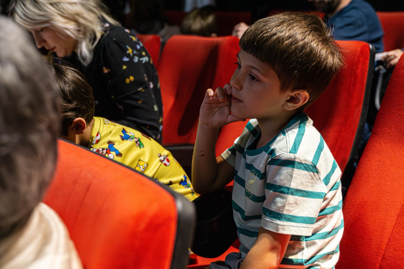 Un bambino al cinema, sulle poltrone rosse