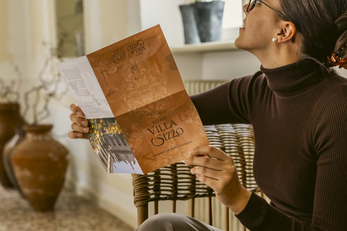 Una ragazza sfoglia la brochure di Villa Sizzo in salotto
