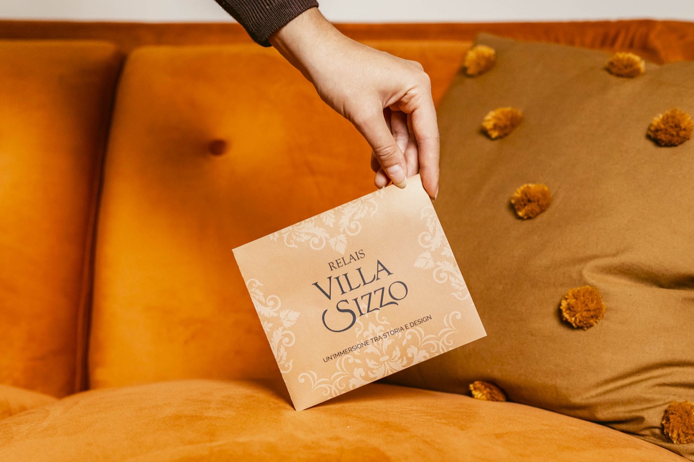 Una mano appoggia la brochure sul divano